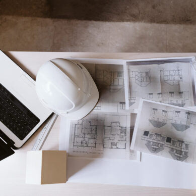 blueprints, protective helmet, laptop,house model and tools on architect workspace.Construction site